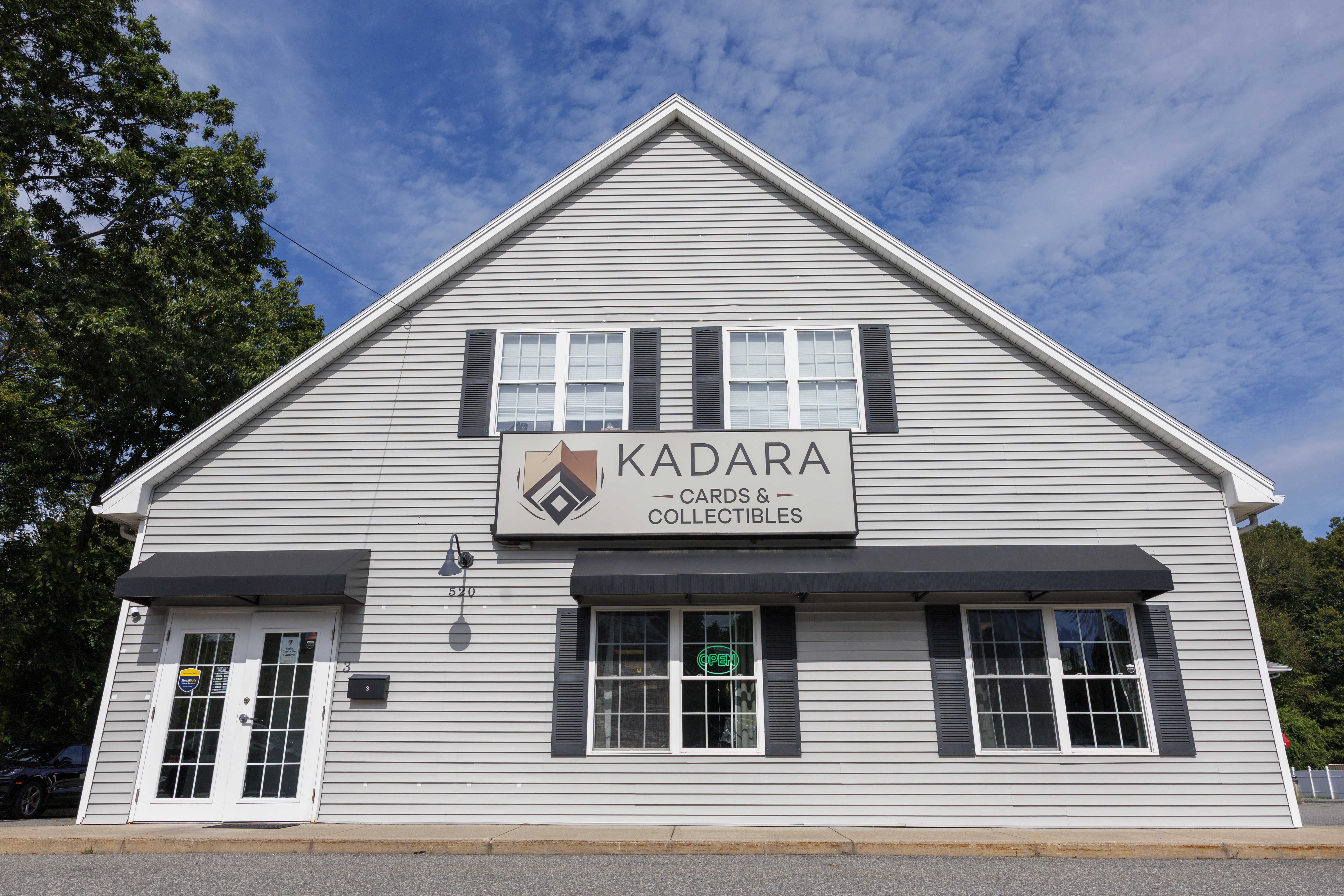 Exterior of Kadara Cards & Collectibles at 520 Main Street in Wilmington, with the store sign, black awnings, and an OPEN sign in the window.