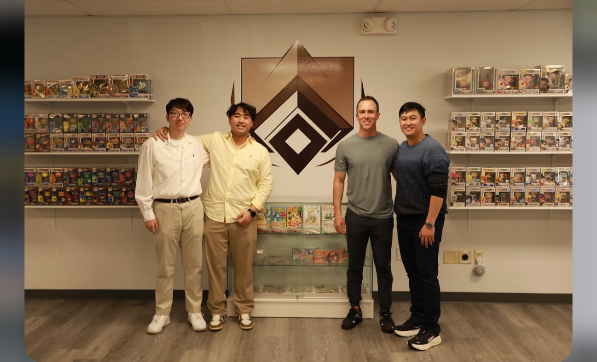 The Kadara Cards team in the Wilmington shop, standing in front of the store logo and collectibles displays.